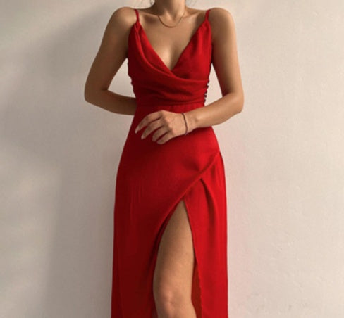 A woman wearing an red long sleeveless dress with a deep v-neckline and a side slit.