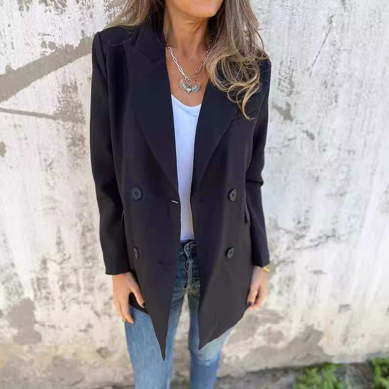 A woman wearing a black Urban Grace Lapel Jacket with a white top and blue jeans. She has accessorized with a necklace and has convenient pockets on the jacket.