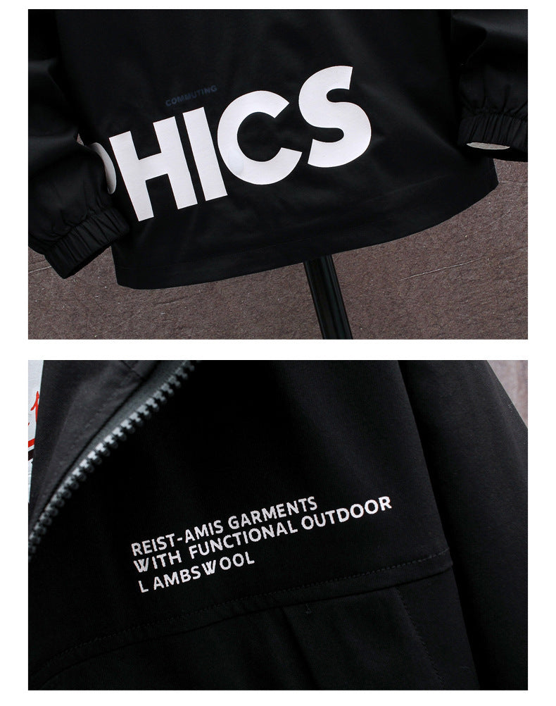 A plus-sized black jacket with a hood, featuring white graphic prints on the chest and a zipper closure. The jacket is displayed on a mannequin against a room setting with a decorative plant and a wall.