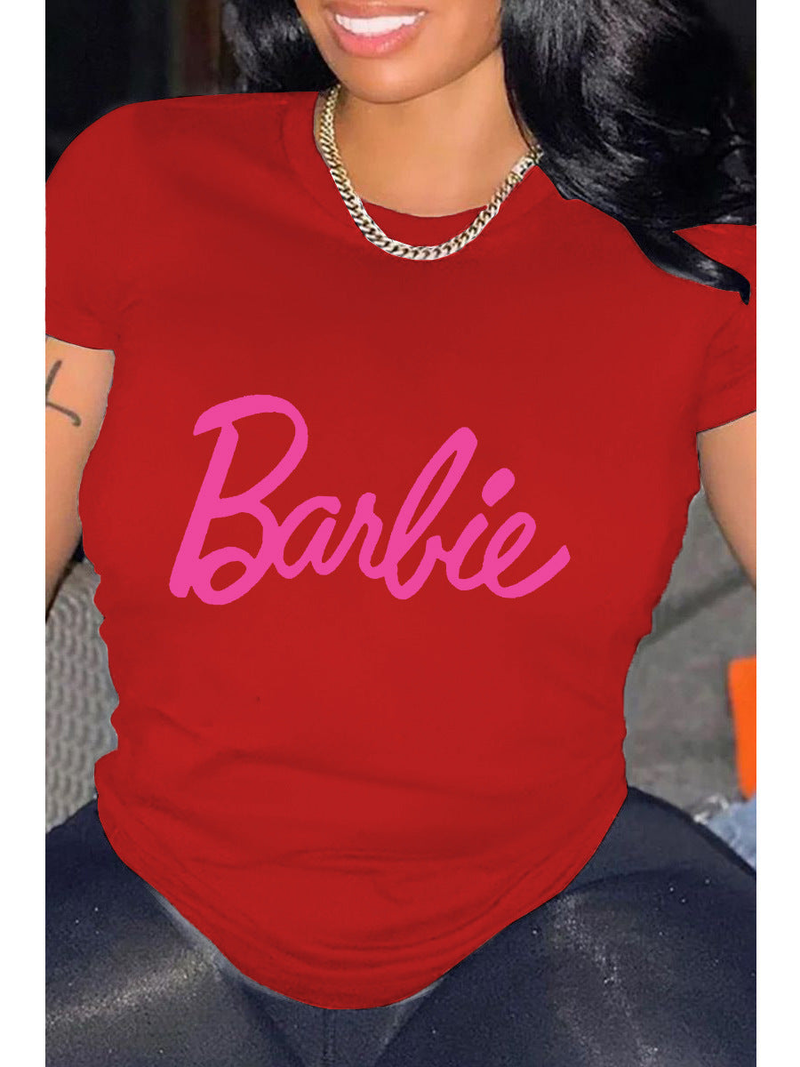 A person wearing a red relaxed fit t-shirt with the pink 'Barbie' text graphic printed on the front.