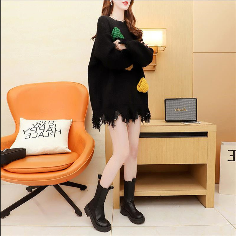 A woman wearing a black festive flair loose sweater with three-dimensional decoration, sitting on an orange sofa.