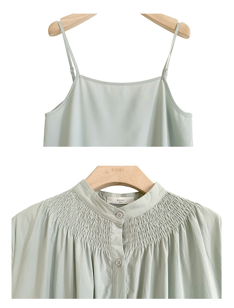 A woman sitting at a table wearing a white midi-length pleated dress with a round neckline and long sleeves.