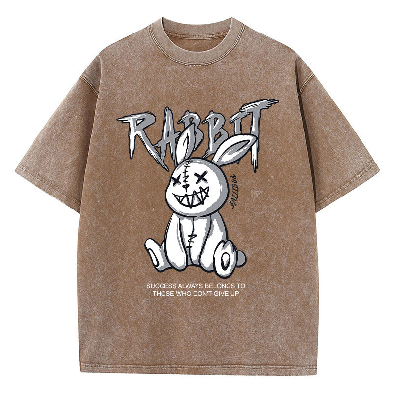 A brown T-shirt featuring a graphic print of a stylized rabbit with the text 'RABBIT' above it. The graphic has a black and white color scheme.