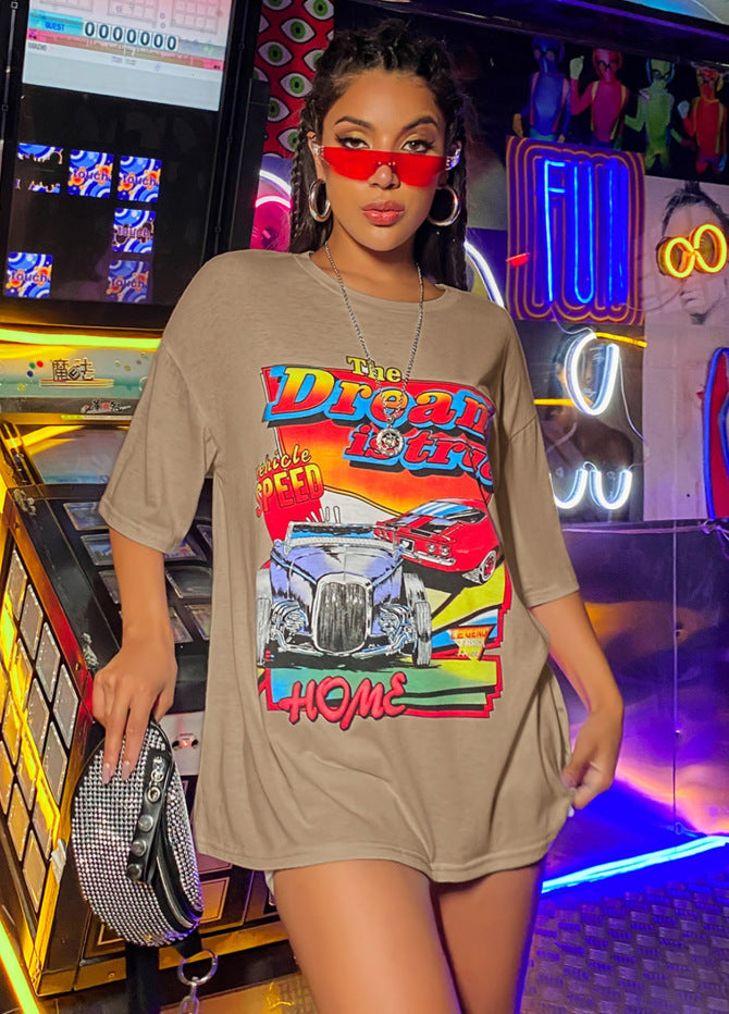A woman wearing an oversized top with a graphic print, paired with shorts and red sunglasses.