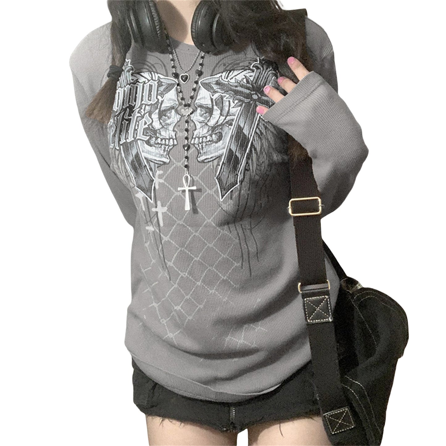 Person wearing a gray hoodie with a skull design, holding headphones, and carrying a black bag.