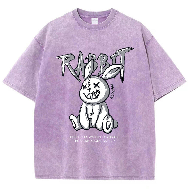 A pink T-shirt featuring a graphic print of a stylized rabbit with the text 'RABBIT' above it. The graphic has a black and white color scheme.