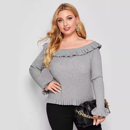 A woman wearing a gray off-shoulder sweater with ruffle detailing and long sleeves.