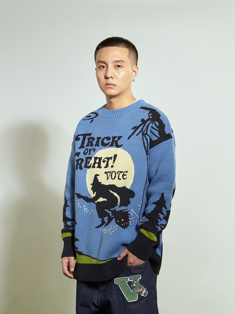 Person wearing a blue sweater with Halloween-themed design on a plain background