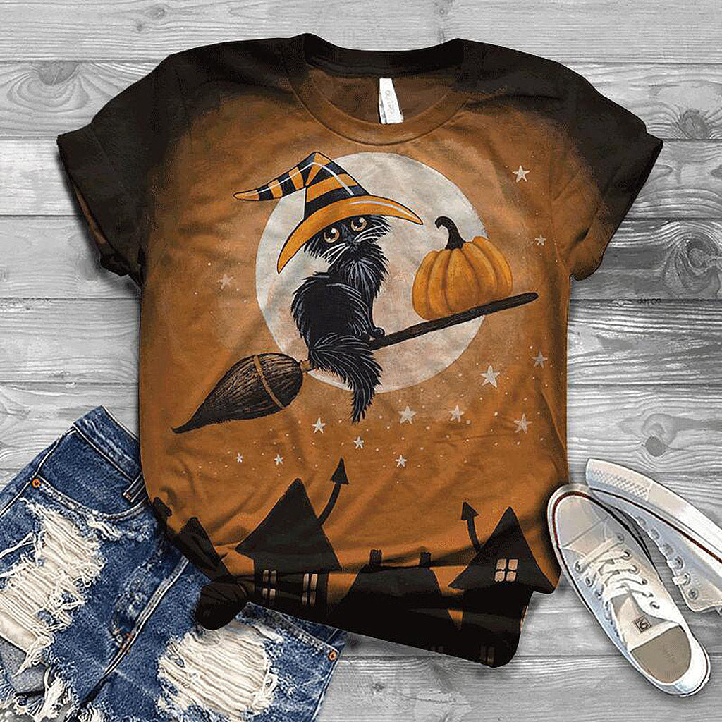 Halloween-themed t-shirt with a crow, pumpkin, and witch hat design on a wooden surface.