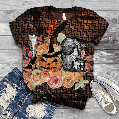Halloween-themed t-shirt with pumpkins, cats, and flowers on a wooden surface with jeans and sneakers.