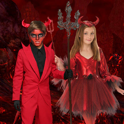 Two children in red devil costumes with horns and a trident against a fiery background.