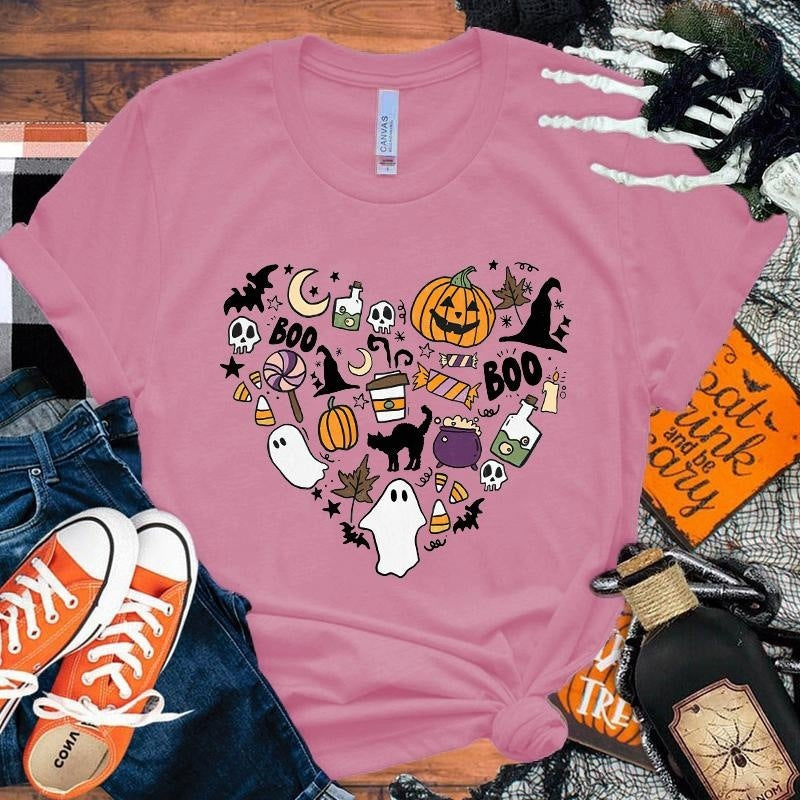 Pink t-shirt with Halloween-themed design on a wooden surface with accessories.