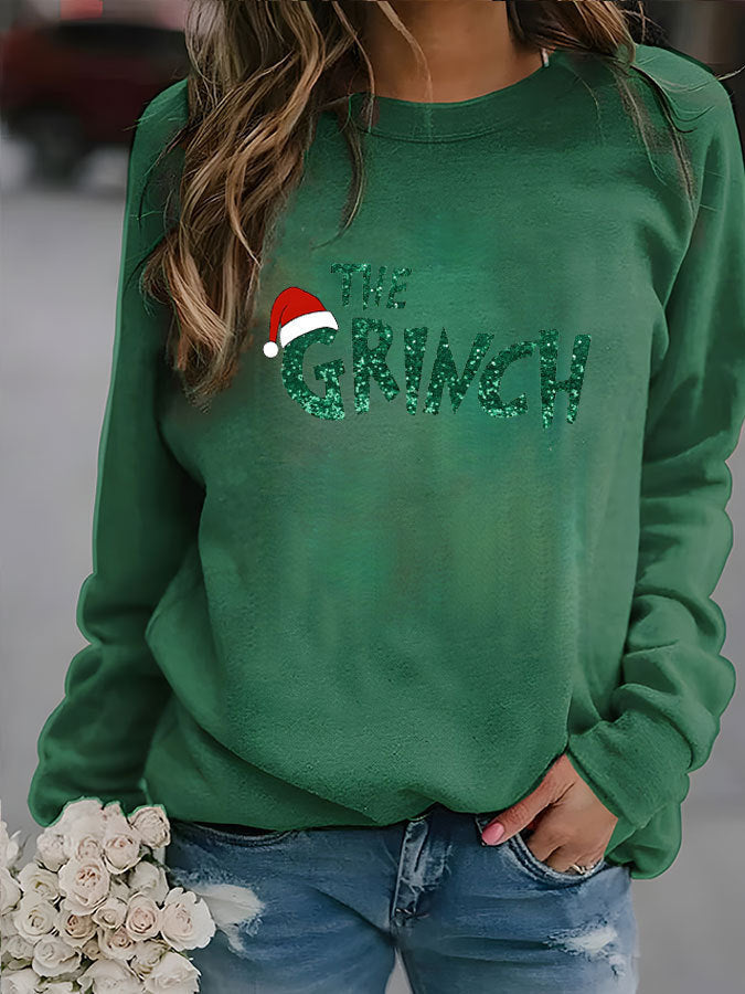 Green sweatshirt with 'The Grinch' text and Santa hat graphic, worn by a person.
