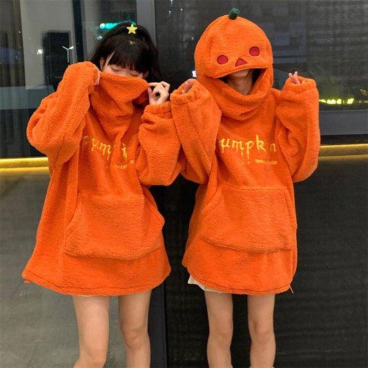 Two people wearing orange hoodies with 'Pumpkin' text, standing in front of a reflective surface.