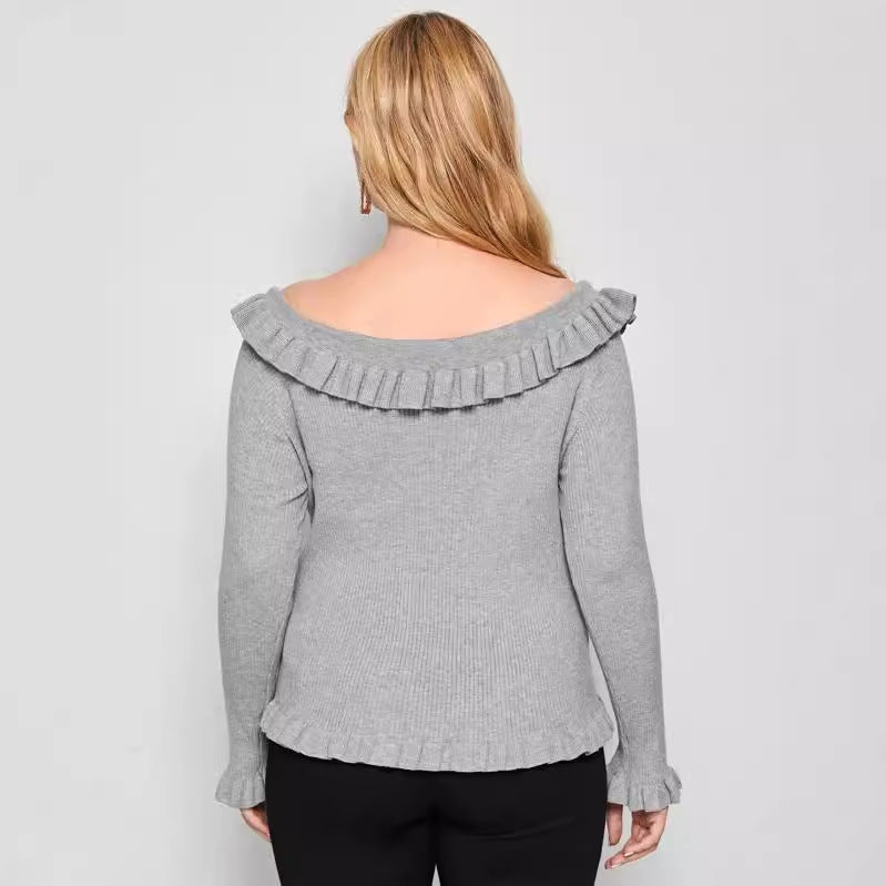 A woman wearing a gray off-shoulder sweater with ruffle detailing and long sleeves.