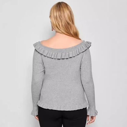 A woman wearing a gray off-shoulder sweater with ruffle detailing and long sleeves.