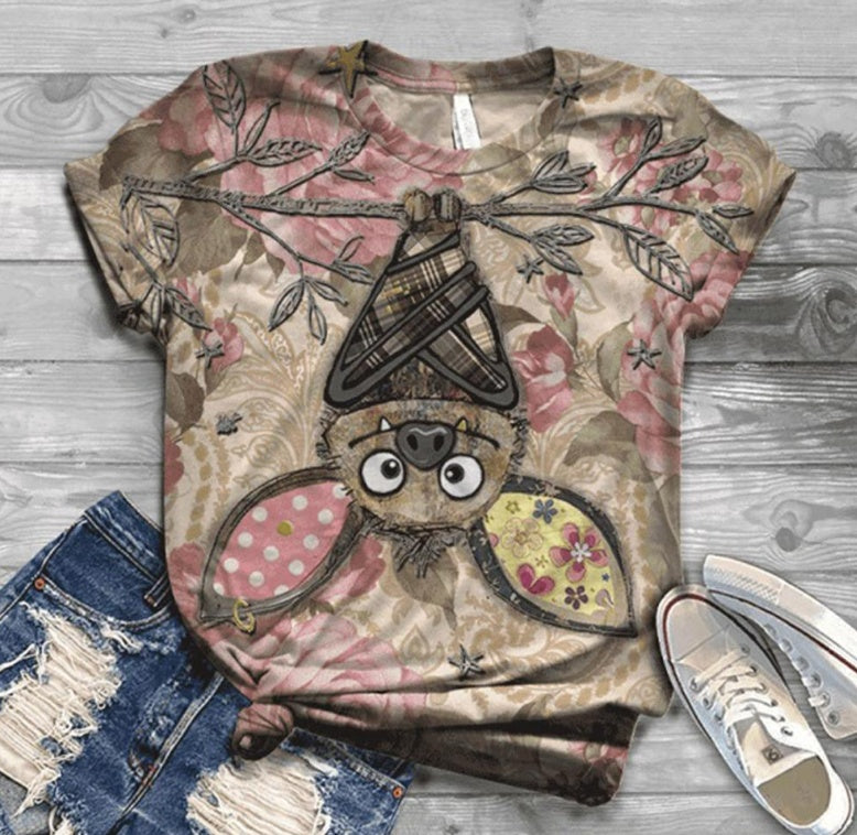 T-shirt with a bat design on a wooden surface with jeans and shoes.