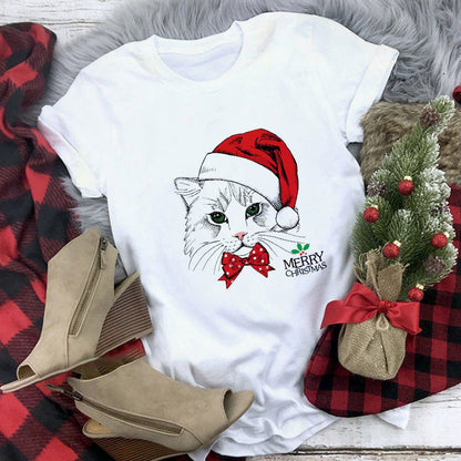 White t-shirt with a cat wearing a Santa hat and 'Merry Christmas' text, surrounded by festive items on a checkered fabric background.