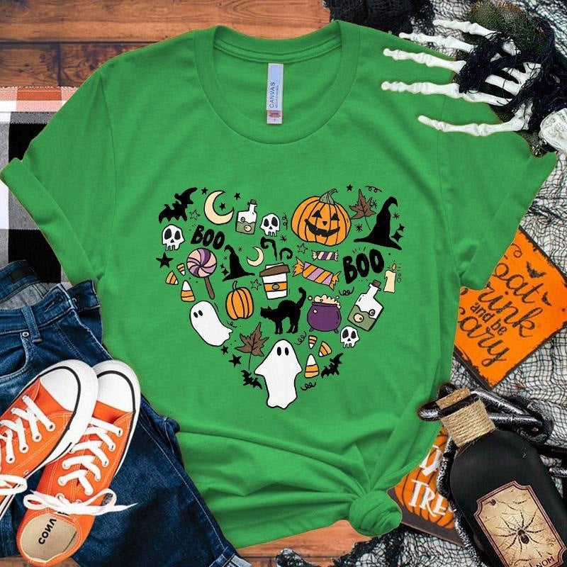 Green t-shirt with Halloween-themed design on a wooden surface with accessories.