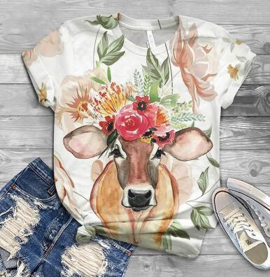 T-shirt with a cow design wearing a floral headband on a wooden surface.