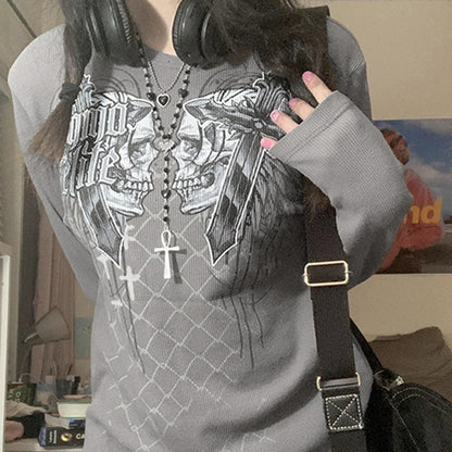 Person wearing a gray hoodie with a graphic design, holding headphones, in an indoor setting.