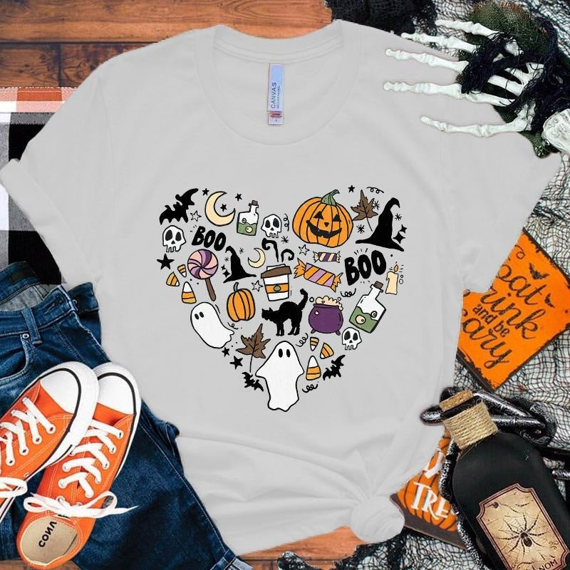 White t-shirt with Halloween-themed design, orange sneakers, and decorative items on a wooden surface.