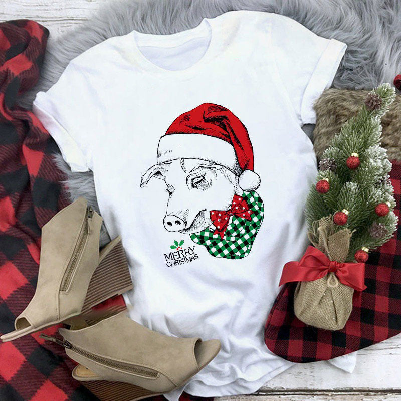 White t-shirt with a Christmas-themed pig design on a red and black checkered fabric background.