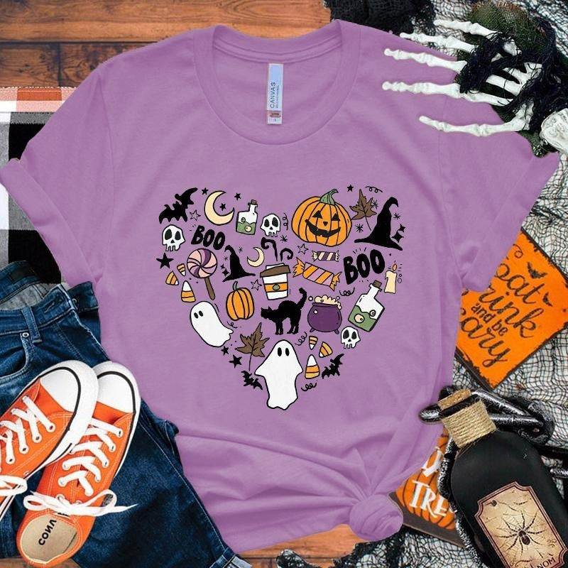 Purple t-shirt with Halloween-themed design on a wooden surface with accessories.
