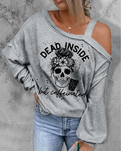 Gray sweatshirt with skull and coffee graphic and text 'Dead Inside but Caffeinated' worn by a person against a gray background.