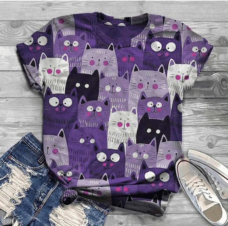 Purple t-shirt with cat pattern on a wooden surface with jeans and sneakers.