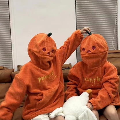 Two children wearing orange hoodies with pumpkin designs and 'pumpkin' text, sitting on a couch.