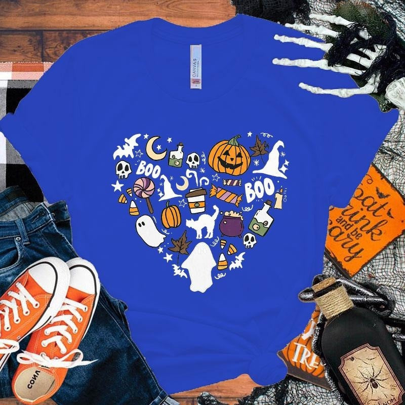 Blue t-shirt with Halloween-themed design on a wooden surface with accessories.