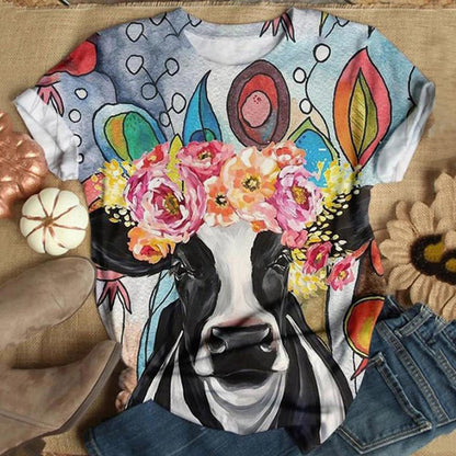 T-shirt with a colorful cow design wearing a flower crown on a wooden surface.