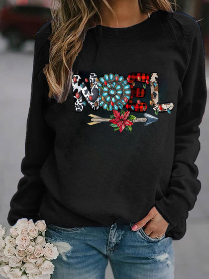 Black sweatshirt with decorative text and graphics worn by a person, with a blurred background.