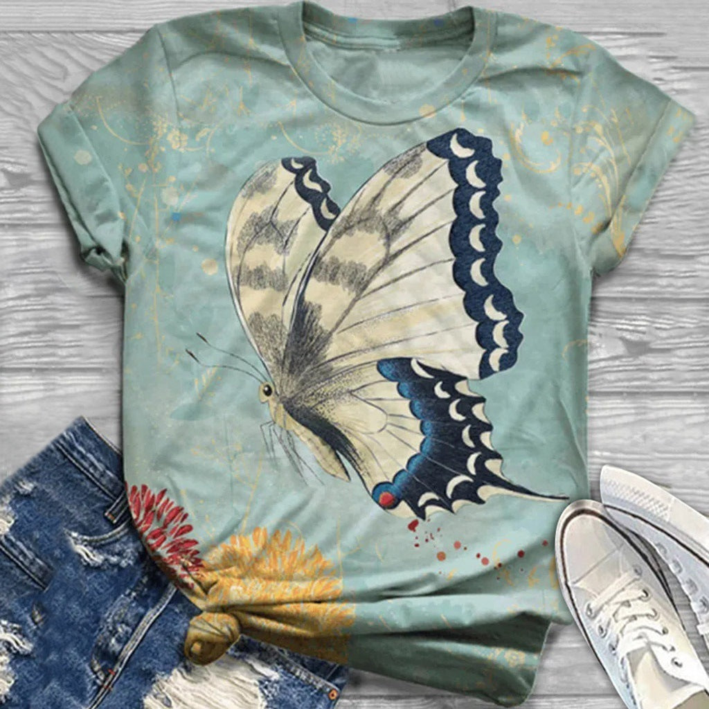 T-shirt with butterfly design on a wooden surface with jeans and shoes.