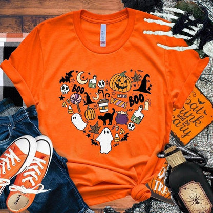 Orange t-shirt with Halloween-themed graphics on a wooden surface with accessories.